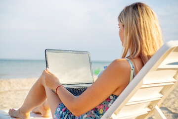 Beautiful young woman working with laptop on the tropical beach. Successful person concept