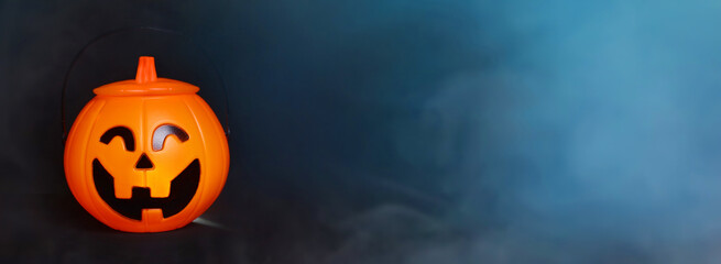 Glowing Halloween handbag in the form of a pumpkin on a background of blue smoke and fog.Halloween trick or treat!?opy space for text. Banner