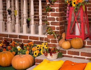The porch of the house is decorated with pumpkins, flowers, grapes, sunflowers, a basket of rowan...