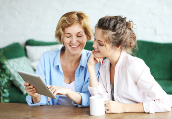 lifestyle, technology and people concept: mother and adult daughter using tablet computer at home