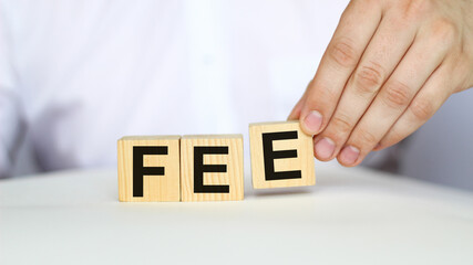 A businessman holds wooden cubes with a word FEE on a white background, with space to copy the text, business concept