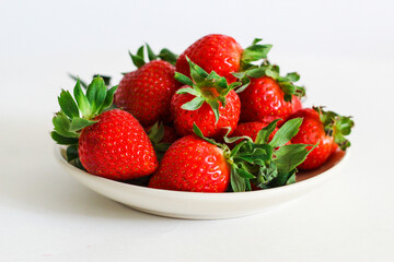 Strawberry berry with green leaf in a plate, isolated on a white background, white table. berries and food
