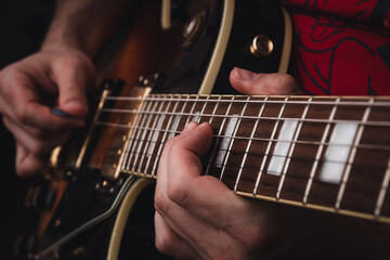 Person plucking the strings on the frets of an electric guitar. Selective focus. Copy space.