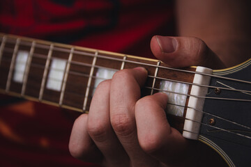 Person plucking the strings on the frets of an electric guitar. Selective focus. Copy space.