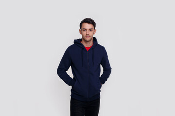 Obraz na płótnie Canvas Frontal image of a smiling handsome young brunette man in dark blue jumper and jeans over white wall background.