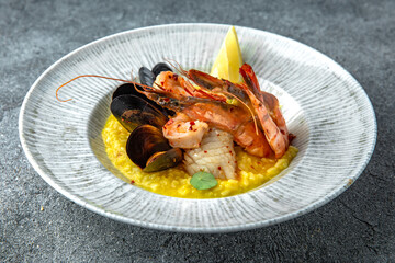 Risotto of seafood in champagne. Shrimps, mussels, squid. Ready menu for the restaurant. Neutral gray blue textured background