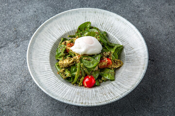 Salad with spinach, eggplant, tomatoes, poached eggs. Diet healthy nutritious food. Ready menu for the restaurant. Neutral gray blue textured background
