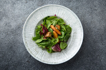 Hearty salad with wild mushrooms, baked potatoes, spinach sauce. Diet food. Ready menu for the restaurant. Neutral gray blue textured background