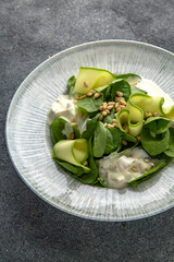 Hearty salad with mushrooms and chicken in a creamy sauce, zucchini and spinach with pine nuts. Diet food. Ready menu for the restaurant. Neutral gray blue textured background