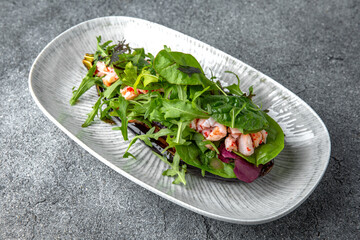 Baked eggplant with arugula, shrimps, tobiko caviar pate. Ready menu for the restaurant. Neutral gray blue textured background