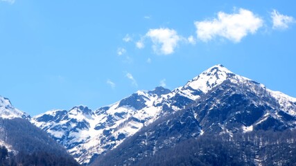 beautiful landscape of snow-capped mountains with white clouds on blue sky on a sunny day at Krasnaya Polyana in Sochi, Russia. Famous ski resort