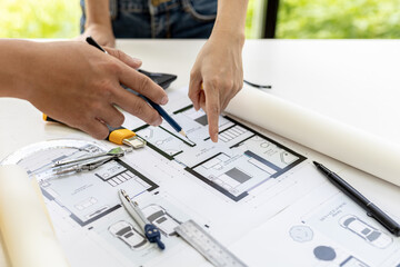 Engineers and architects pointing to the house blueprints designed for the client, meeting atmosphere, they meet together to plan the construction and fix it. Design and interior design ideas.