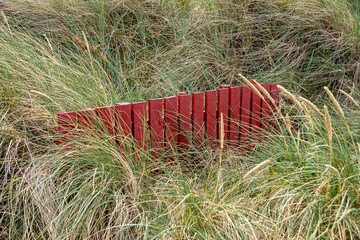 Red fence in the middle of dune grass at the north sea coast in Denmark 
