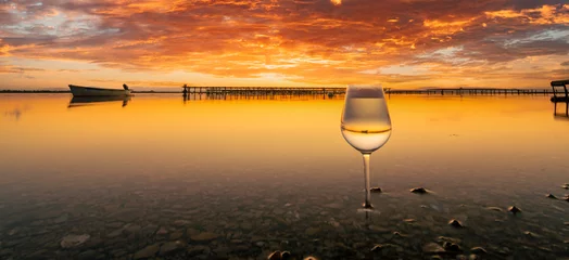 Fotobehang Verre à vin sur fond d'étang au coucher de soleil. © ODIN Daniel