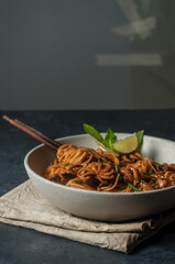 spicy asian noodles with baby octopus side view on gray background closeup. Selective focus