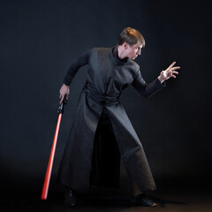 A villain with a red lightsaber, a young man in a long robe does fighting poses, - 459249461