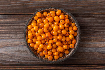 Fresh ripe autumn sea buckthorn berries on wooden background. Top view