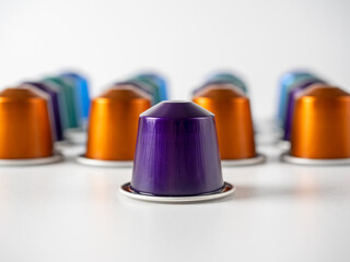 Colorful aluminum capsules with ground coffee on a white background. One purple in the foreground. Capsules for the coffee machine