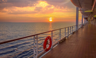 Pont promenade d'un navire de croisière en navigation avec coucher de soleil.	