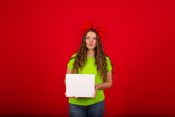 a girl with a red bow on her head in a light green T-shirt in blue jeans holds a white sheet of paper