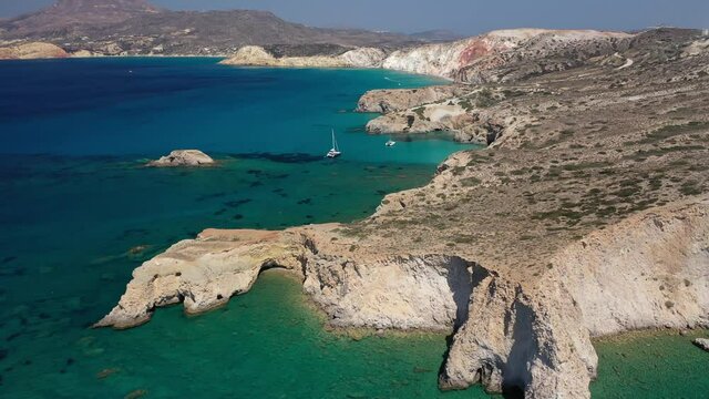 Aerial drone video of beautiful scenic rocky cove and beach of Tsigrado with caves and crystal clear emerald sea, Milos island, Cyclades, Greece