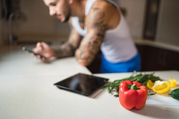 Verduras de colores en encimera de cocina  junto a un smartphone para subir contenido a redes...