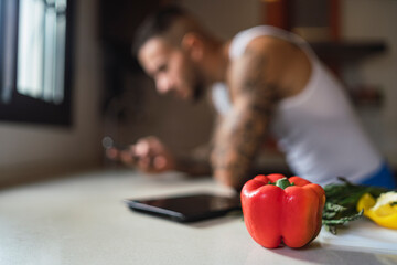 Verduras de colores en encimera de cocina  junto a un smartphone para subir contenido a redes...