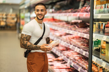Chico atlético fitness tatuado comprando en un supermercado