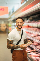 Chico atlético fitness tatuado comprando en un supermercado