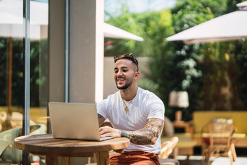 Chico atletico fitness trabajando con un portatil en una terraza soleada