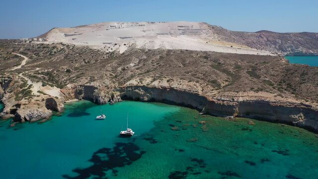 Aerial drone video of beautiful scenic rocky cove and beach of Tsigrado with caves and crystal clear emerald sea, Milos island, Cyclades, Greece