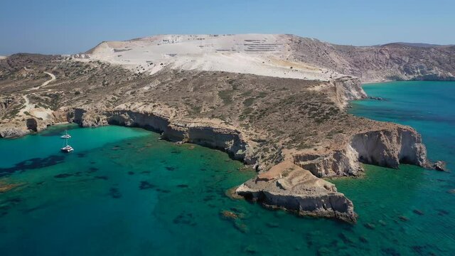 Aerial drone video of beautiful scenic rocky cove and beach of Tsigrado with caves and crystal clear emerald sea, Milos island, Cyclades, Greece