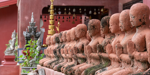 Scenic row of old terracotta statues of monks in prayer at ancient Wat Phan Tao buddhist temple,...