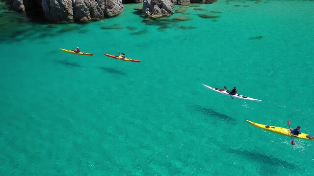 Aerial drone video of women team of sport kayak in iconic beach and small cove of Tsigrado, Milos island, Cyclades, Greece