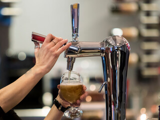 persona en un bar tirando una vaso de cerveza fria en un grifo de cervezas en la barra