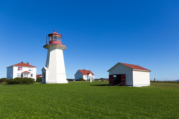The 1939 Cap-d’Espoir octogonal red and white concrete lighthouse and keeper’s house seen during a sunny summer day, Percé, Quebec, Canada