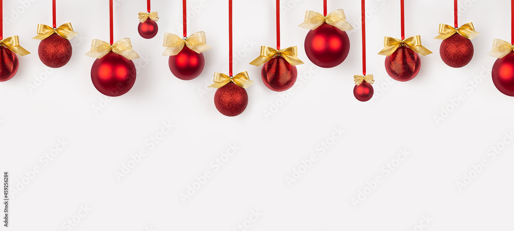 Poster christmas banner in simple minimal style - bright red balls with golden bows hanging on ribbon in ro
