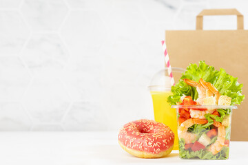 Healthy fitness food - set of orange juice, tropical shrimp salad in box, pink donut, packet in white interior. Mockup advertising for delivery service, take away restaurant, online order.