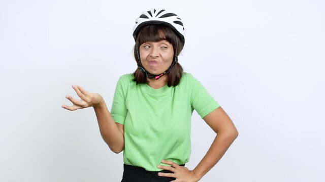 Young woman with bike helmet over isolated background making unimportant and doubts gesture while lifting the shoulders and the palms of the hands over isolated background