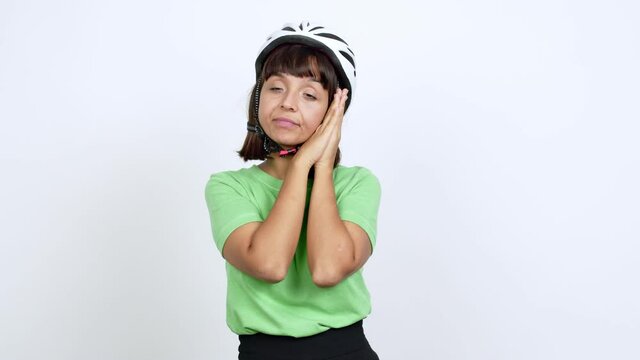 Young woman with bike helmet over isolated background making sleep gesture. Adorable and sweet expression over isolated background