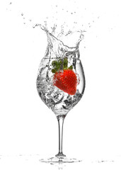 Strawberry splashing into an ice-cold cocktail glass isolated on white background