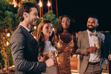 Group of beautiful young people in formalwear communicating and smiling while spending time on...