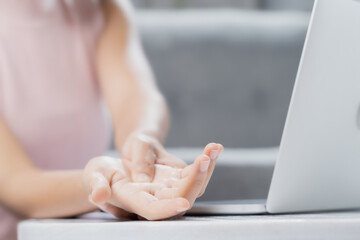 A young woman is having hand pain from using a laptop.