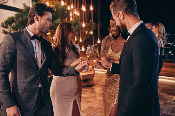 Group of people in formalwear toasting with champagne and smiling while spending time on luxury...