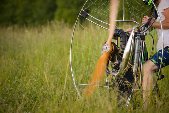 The pilot is preparing a paralet with a gasoline engine for flights. The man is warming up the engine. Motorized equipment for individual paragliding flights. Extreme sports.