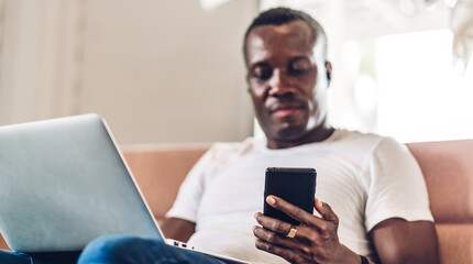Young black african man relaxing using laptop computer working and video conference meeting at home.Young creative african man talk with smartphone.work from home concept