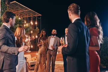 Group of beautiful people in formalwear communicating and smiling while spending time on luxury party