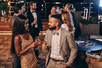 Beautiful young African couple in formalwear holding champagne flutes and smiling