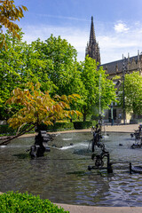 Playful trick fountains at Fasnachtsbrunnen (carnival fountain), also called Tinguely Brunnen (Tinguely fountain) with the Elisabethenkirche (Elisabethen church) in Basel, Switzerland