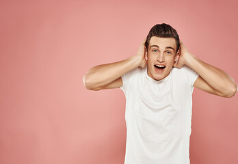 emotional man in white t-shirt gesturing with his hands moda studio pink background